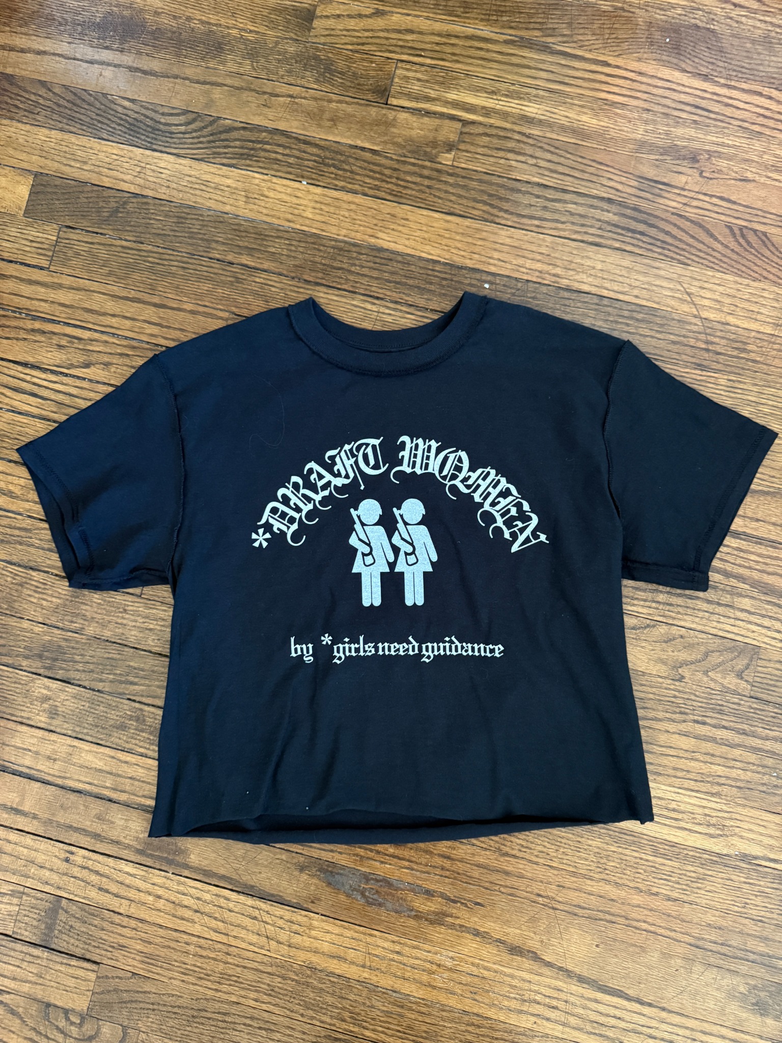 Black Draft Women Old English tee on wood floor.