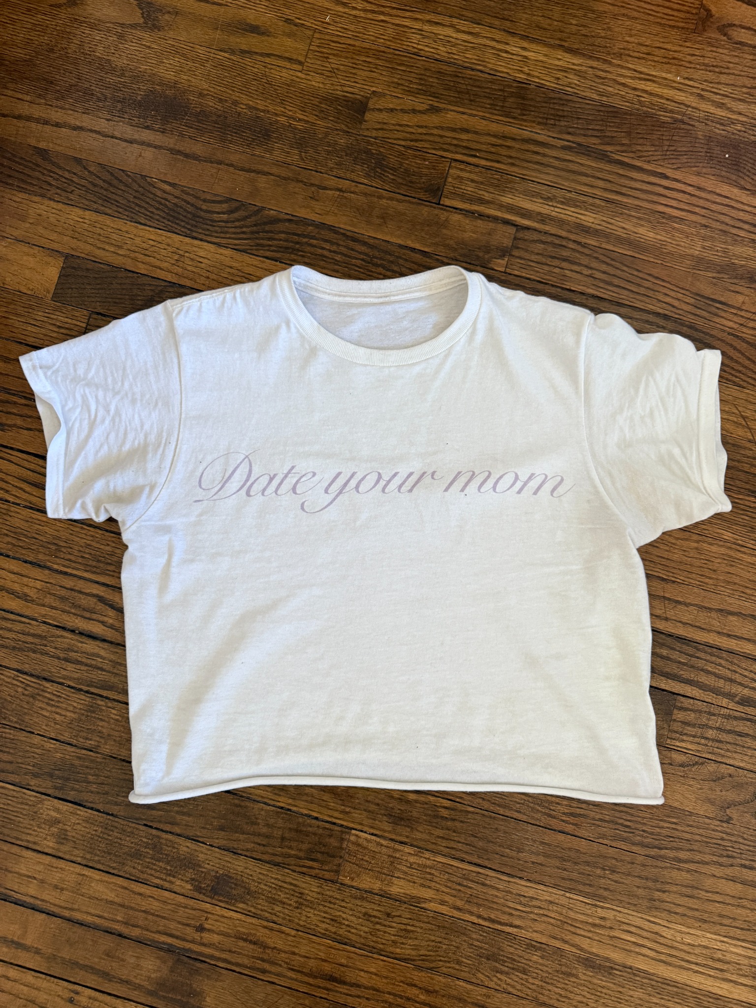 White date your mom crop tee on wood floor.