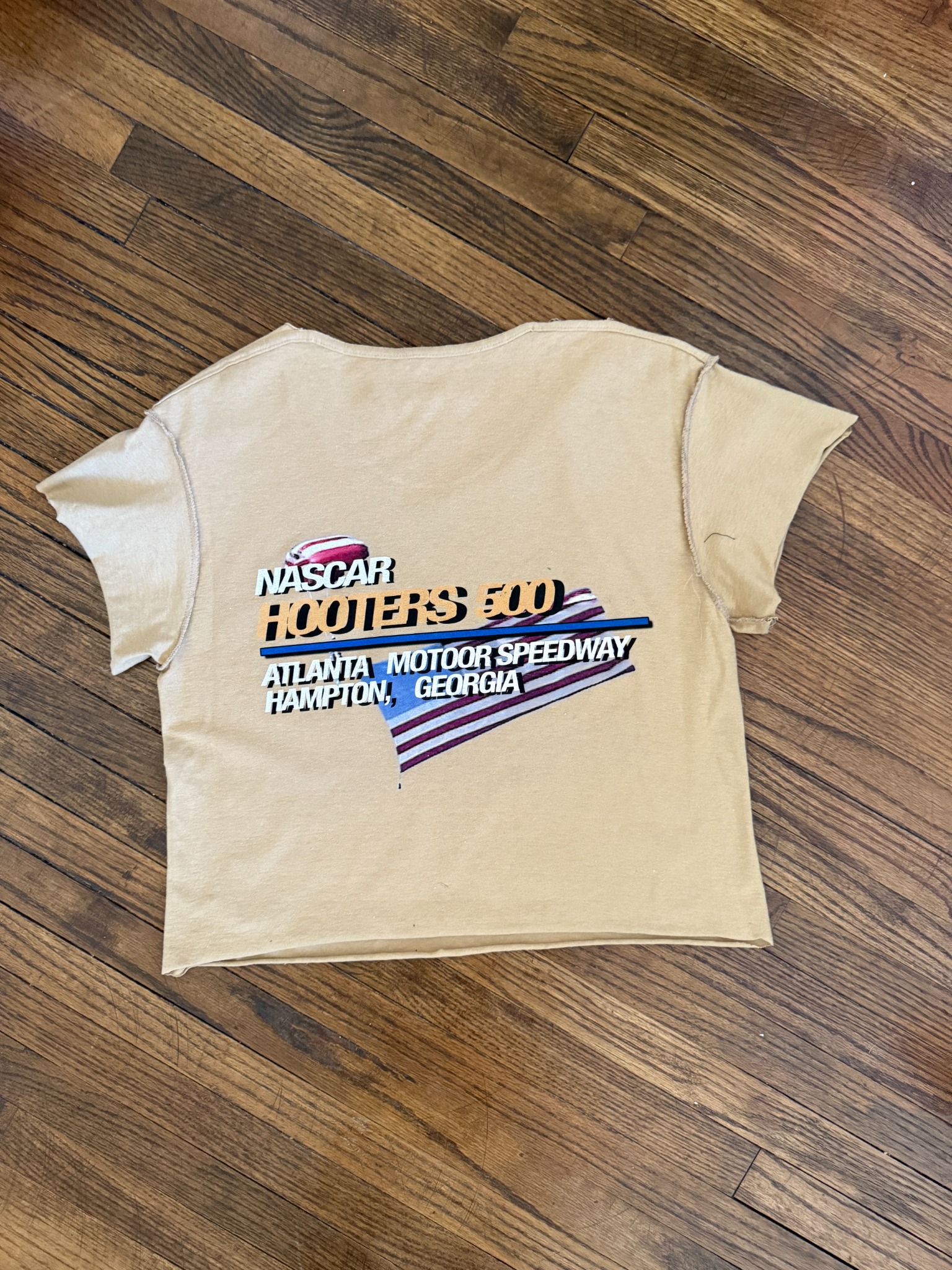 Beige Hooters 500 crop tee back print on wood floor.
